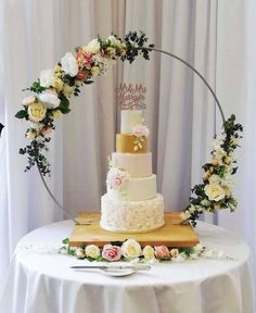 a three tiered wedding cake sitting on top of a wooden table next to flowers