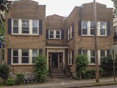 an apartment building with many windows and bushes on the front