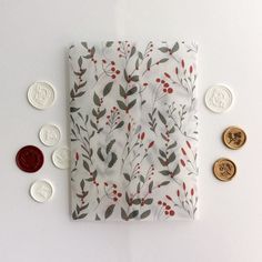 a white napkin with red berries and green leaves on it next to some gold coins