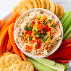 a platter with crackers, carrots, celery, and dip