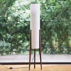 a floor lamp sitting on top of a hard wood floor next to a large window