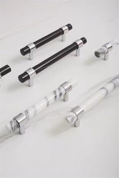 four different types of black and white handles on marbled surfaces, including one in the middle