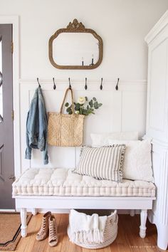 a white bench sitting in front of a door next to a mirror and coat rack