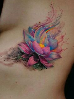 a woman's stomach with a colorful flower tattoo on her side and watercolor splashes