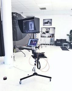 a camera set up in an office with two laptops on the tripod and one monitor