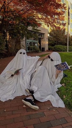 two white cloth covered people sitting on the ground