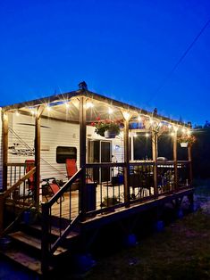 a mobile home is lit up at night with string lights on the porch and deck