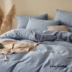 an unmade bed with blue comforter and pillows on the bottom, next to some pamodia