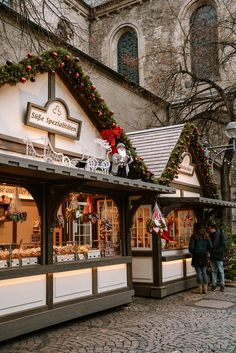 people are standing outside of a store with christmas decorations on the front and side windows