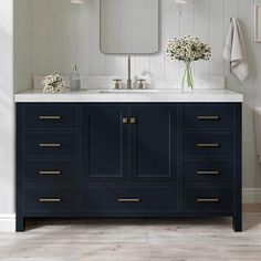 a white toilet sitting next to a blue vanity with two sinks and mirrors above it