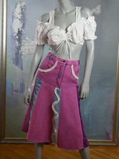 This Italian vintage denim skirt has a unique pink wash, but also features the usual blue jeans denim color on panels on the back and in the front. The stunning skirt has a 1.25-inch (3.18cm) waistband with five belt loops, and closes in the front with a 6.5-inch (16.51cm) zipper and button. The fitted waistline gives way to a semi-flared drop (slightly lower in back than front) to the knee-length hemline. The skirt has two pockets on the front edged in white lace (which also serves as an accent Formal Cocktail Party, Mad Men Dresses, Vintage Denim Skirt, Blue Jean Skirt, Purple Velvet, Jean Skirt, European Vintage, Colored Denim, Vintage Denim