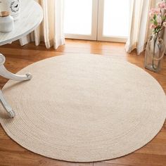 a round rug on the floor in front of a table with vases and flowers