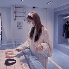 a woman standing in front of a display case with donuts on it's sides