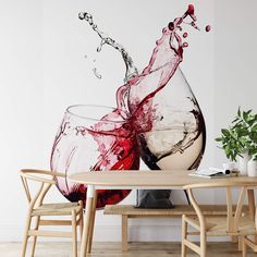 two wine glasses sitting on top of a wooden table next to a potted plant