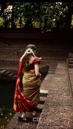 a woman in a sari is sitting on the edge of a wall near water