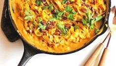 a skillet filled with pasta and garnished with parsley on the side