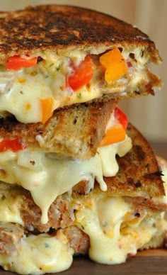 two grilled sandwiches stacked on top of each other with cheese and vegetables in them