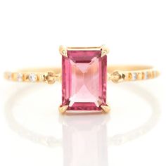 a pink tourmaline and diamond ring on a white background with gold trimmings