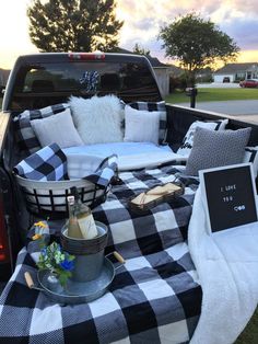 a black and white checkered blanket in the back of a pickup truck with picnic items on it