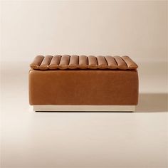 a brown leather bench sitting on top of a white floor next to a beige wall