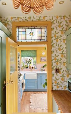 an open door leading to a kitchen with blue cabinets and yellow wallpaper on the walls