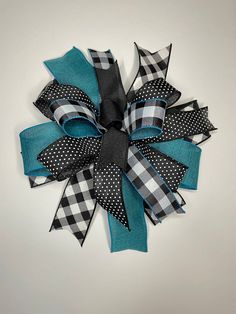 a black, white and blue bow with polka dots on the bottom is hanging from a wall