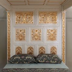 a bed with two pillows on top of it next to a wall mounted paneled headboard