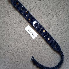 a blue knitted lanyard with a white moon and stars on it, next to a name tag