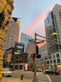 a city street with tall buildings in the background at sunset or sunrise, as seen from across the street