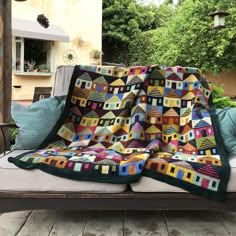 a couch with a quilt on top of it in the middle of a patio area