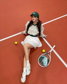 a woman laying on the ground with a tennis racket and ball