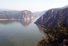 a large body of water surrounded by mountains and trees on the side of a hill