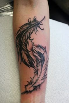 a black and white tattoo on the leg of a person with a feather in it