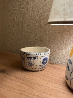 a blue and white bowl sitting on top of a wooden table next to a lamp