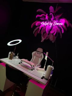 a desk with a chair, lamp and palm tree on it in front of a neon sign