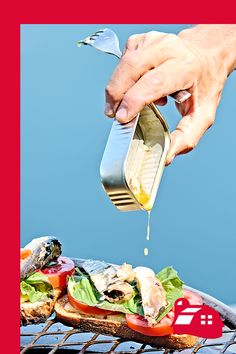 a person pouring dressing onto a sandwich on the grill