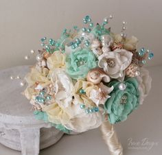 a bridal bouquet with pearls and seashells sits on top of a table