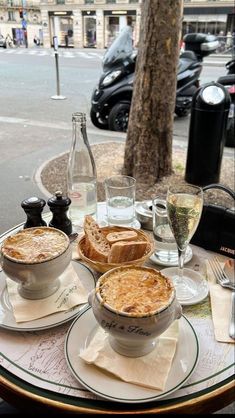 a table topped with plates and bowls filled with food next to a glass of wine