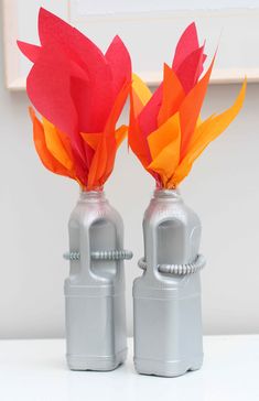 two silver cans with red and orange paper flowers in them