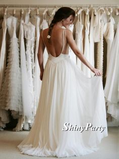 a woman in a white dress looking at wedding gowns