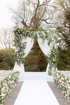 an outdoor ceremony setup with white flowers and greenery