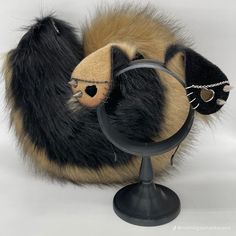 a stuffed animal is sitting on top of a small black stand with a magnifying glass in it's mouth