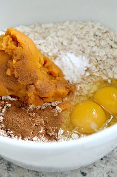 ingredients in a white bowl on top of a granite countertop, including eggs and flour