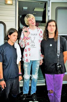 three young men standing next to each other in front of an open door with their hands up