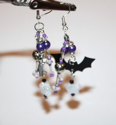 a pair of dangling earrings with beads and bats hanging from it's ear wires