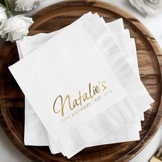 three personalized napkins sitting on top of a wooden plate next to white flowers