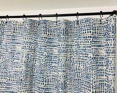 a blue and white curtain hanging from a metal rod