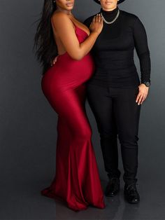 two women standing next to each other in front of a gray background wearing black and red