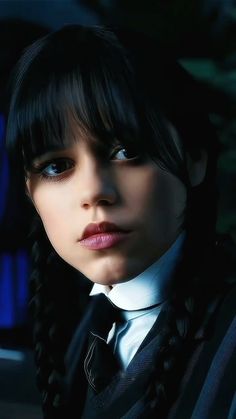 a woman with long black hair and braids wearing a white collared shirt is staring into the distance