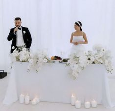 a bride and groom are sitting at a table with candles in front of them,